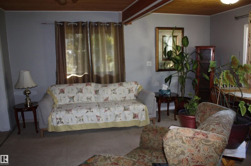 Exposed wood beam ceiling, wood plank ceiling paneling, and neutral wall tones - 5012 49 Ave, Radway, AB 