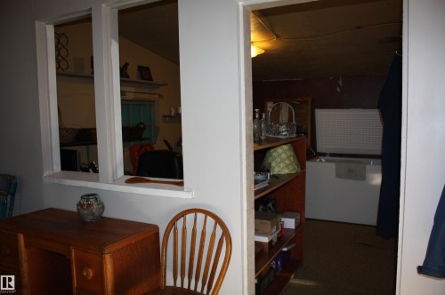Interior wall featuring a pass-through opening with a wide sill and a separate doorway - 5012 49 Ave, Radway, AB 