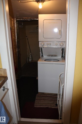 Stacked white laundry center featuring a top-load washer and front-load dryer unit - 5012 49 Ave, Radway, AB 