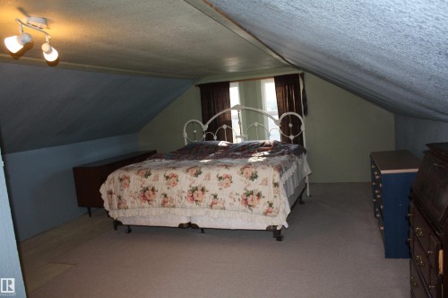 Sloped ceiling design with dual windows and wall-mounted spotlight fixture - 5012 49 Ave, Radway, AB 