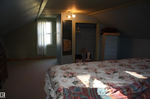 Sloped ceiling, built-in closet with interior rod, recessed wall-mounted mirror, multi-directional ceiling-mounted lighting, and single window with natural light - 5012 49 Ave, Radway, AB 