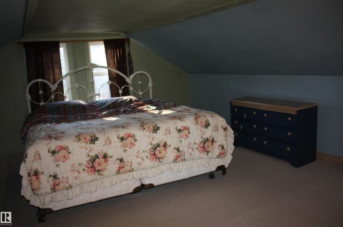 Vaulted ceiling with angled wall lines, carpeted flooring, and dual-pane windows - 5012 49 Ave, Radway, AB 