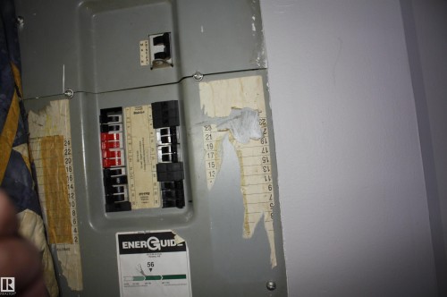 Electrical service panel featuring a central main breaker and multiple individual circuit breakers - 5012 49 Ave, Radway, AB 