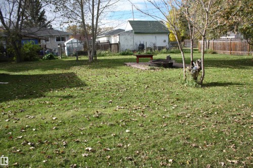 Expansive lawn area with mature trees and a dedicated patio space - 5012 49 Ave, Radway, AB 