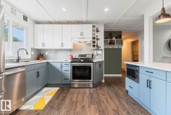 Modern kitchen featuring two-tone cabinetry, stainless steel appliances, wood-finish flooring, and a white subway tile backsplash - 