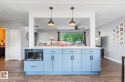 Kitchen island with light blue cabinetry, white countertop, and dark hardware - 