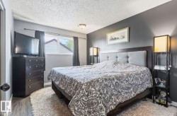 Master bedroom featuring a upholstered headboard bed, dual bedside lighting fixtures, wood-finish flooring, and soft area rug - 