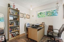 Wood-finish flooring, built-in shelving, white walls, and a window with a white frame - 