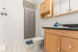 Compact bathroom featuring a shower, toilet, and vanity with light wood-finish cabinetry - 