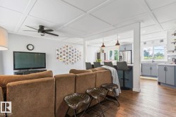 Open-concept living space featuring wood-finish flooring, a coffered ceiling, and a ceiling fan - 