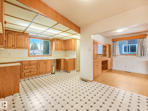 Kitchen featuring extensive wood cabinetry, white tile backsplash, and patterned floor tiling - 5904 94 Avenue Nw, Edmonton, AB 