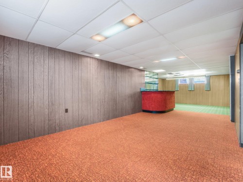 Wood-paneled walls, drop ceiling with recessed lighting, integrated bar area, and carpeted flooring - 5904 94 Avenue Nw, Edmonton, AB 