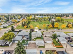 Property featuring a pitched roof, front yard, established trees, and a concrete driveway - 