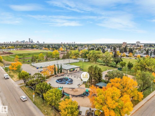 City skyline visible in the distance, expansive green spaces, sports courts, and a playground area - 5904 94 Avenue Nw, Edmonton, AB 