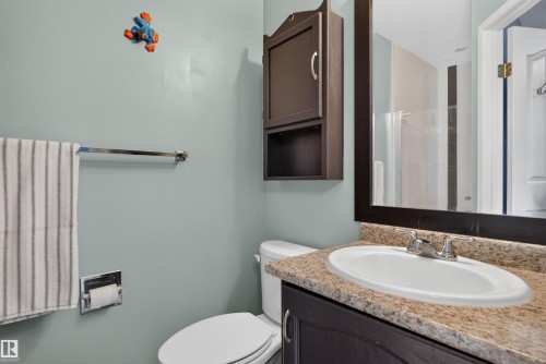 Vanity with an integrated sink and light-toned countertop, framed mirror, and wall-mounted storage cabinet - 1519 104 Street Nw, Edmonton, AB 