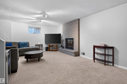 Carpeted floor, track lighting, brick fireplace with metal insert, and white walls - 1519 104 Street Nw, Edmonton, AB 