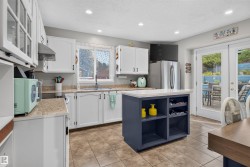Kitchen featuring white cabinetry, a central island with integrated storage, tile flooring, and light-toned countertops - 