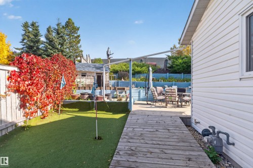 Backyard featuring a synthetic turf putting green, a wooden walkway, and a concrete patio area - 1519 104 Street Nw, Edmonton, AB 