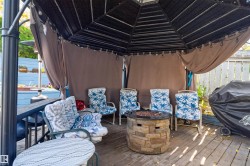 Expansive outdoor deck featuring a gazebo, stone-clad fire pit, and wood plank flooring - 
