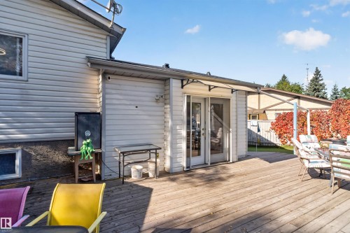 Expansive wood-finish deck with white vinyl siding exterior and multi-panel glass doors - 1519 104 Street Nw, Edmonton, AB 