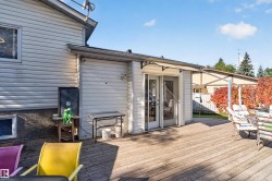 Expansive wood-finish deck with white vinyl siding exterior and multi-panel glass doors - 