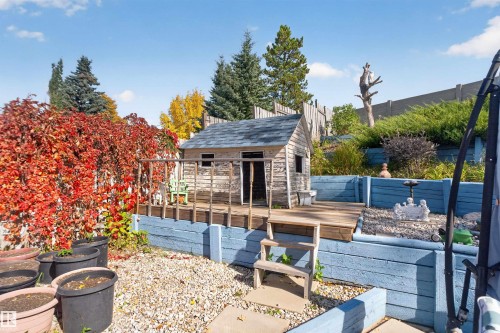 Tiered backyard featuring a wooden playhouse, wood decking, and a gravel ground cover - 1519 104 Street Nw, Edmonton, AB 