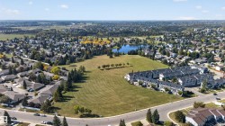 Expansive open field with surrounding residential properties, mature trees, and a lake - 