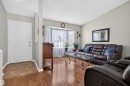 Open concept living area featuring hardwood-finish flooring, a bay window with natural light, and a white paneled entry door - 1519 104 Street Nw, Edmonton, AB 