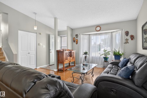 Recessed bay window, wood-finish flooring, light grey wall paint, white trim, and a contemporary pendant light fixture - 1519 104 Street Nw, Edmonton, AB 