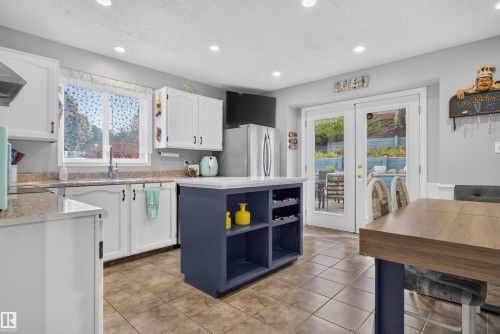 White cabinetry, tile flooring, recessed lighting, and a kitchen island with built-in shelving - 1519 104 Street Nw, Edmonton, AB 
