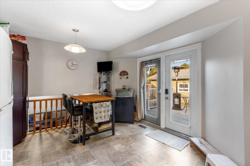 Tiled flooring, built-in cabinetry, pendant lighting, and double glass panel doors leading to an exterior deck - 4103 44 Avenue, Stony Plain, AB 