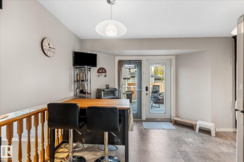 Wood-finish flooring, built-in breakfast bar, pendant lighting, full-light exterior door, and wood railing - 4103 44 Avenue, Stony Plain, AB 