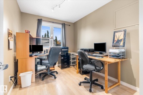 Wood-finish flooring, neutral wall color, and a window with a dark-colored curtain rod and drapes - 4103 44 Avenue, Stony Plain, AB 