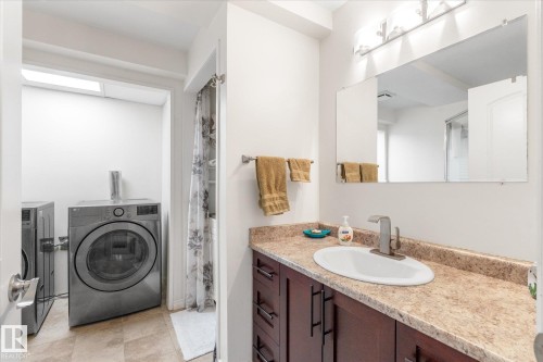 Bathroom featuring a brown-finish vanity with a single basin sink and a stone-finish countertop - 4103 44 Avenue, Stony Plain, AB 