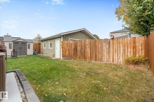 Expansive backyard with a manicured lawn, wood fencing, and a detached structure with siding - 4103 44 Avenue, Stony Plain, AB 