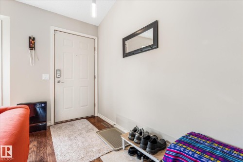 Paneled entry door with smart lock, wood-finish flooring, and a wall-mounted mirror - 4103 44 Avenue, Stony Plain, AB 