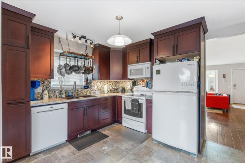 Kitchen featuring wood cabinetry, integrated appliances, mosaic tile backsplash, and tile flooring - 4103 44 Avenue, Stony Plain, AB 