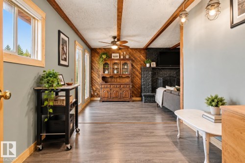 Wood-finish flooring throughout, exposed wood beams, and a black brick fireplace - 62202 Rr 444, Rural Bonnyville M.D., AB 