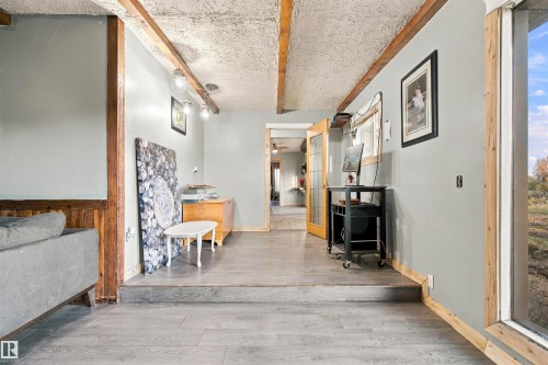 Wood-finish flooring, exposed ceiling beams, wood-paneled walls, built-in wall lighting, and a large picture window - 62202 Rr 444, Rural Bonnyville M.D., AB 
