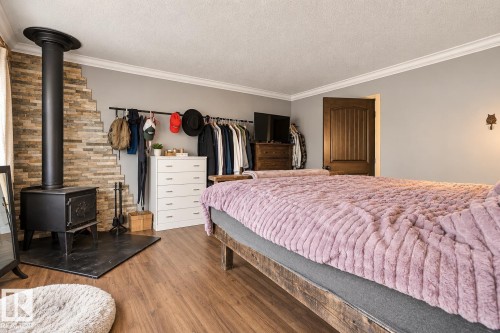 Wood-finish flooring with a black wood-burning stove and stone-finish wall accent - 62202 Rr 444, Rural Bonnyville M.D., AB 