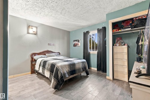 Wood-finish flooring, single window with natural light, wall-mounted light fixture, built-in closet with shelving, and contrasting wall colors - 62202 Rr 444, Rural Bonnyville M.D., AB 