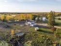 White exterior home with multiple outbuildings, bordered by mature trees and a natural water feature - 62202 Rr 444, Rural Bonnyville M.D., AB 