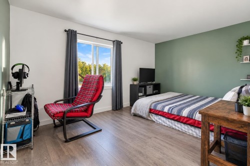 Wood-finish flooring throughout, a large window with roller shades, and a feature wall - 62202 Rr 444, Rural Bonnyville M.D., AB 