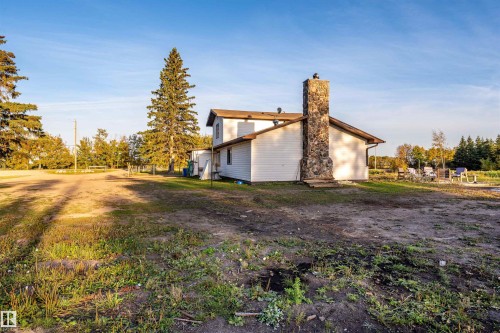 White siding exterior featuring a prominent stone chimney - 62202 Rr 444, Rural Bonnyville M.D., AB 