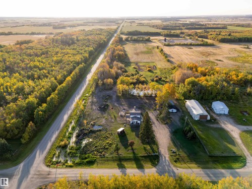 Expansive rural property featuring a primary residence, two outbuildings, a paved road, and abundant mature trees - 62202 Rr 444, Rural Bonnyville M.D., AB 