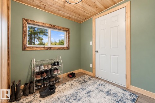 Wood-finish flooring with coordinating wood trim, a paneled door, and a horizontal window with a distressed wood-finish frame - 62202 Rr 444, Rural Bonnyville M.D., AB 
