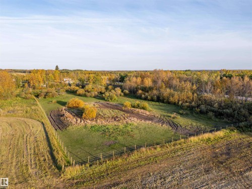 Expansive lot featuring a perimeter fence, varied topography, and a backdrop of mature trees - 62202 Rr 444, Rural Bonnyville M.D., AB 