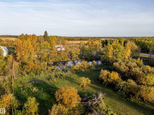 Expansive acreage featuring abundant mature trees, a natural pond, and a large greenhouse structure - 62202 Rr 444, Rural Bonnyville M.D., AB 