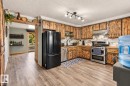Kitchen featuring wood-finish cabinetry, wood-finish countertops, stainless steel appliances, a tile backsplash, and wood-finish flooring - 62202 Rr 444, Rural Bonnyville M.D., AB 