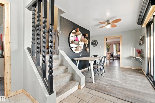 Carpeted staircase with black wood balusters, tile entry, and wood-finish flooring - 62202 Rr 444, Rural Bonnyville M.D., AB 